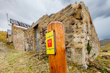 CAMP DES FOURCHES, FRANCE - AUGUST 30, 2019: GR 5 long distance footpath marker, abandoned WWII army barracks, Mercantour National Park mountains, French Alps, Provence, France