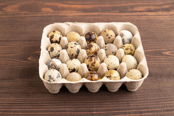 Pile of raw quail eggs on brown wooden. side view, copy space.