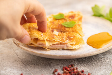 Fried homemade khachapuri cake with hand with cheese and meat, fried in pan. Side view, selective focus