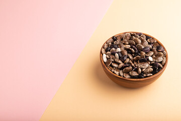 wooden bowl with Kidney beans on pink and orange pastel paper, side view, copy space