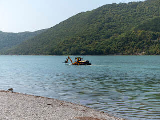 Abrau Durso, Russia 28 August 2024: Municipal aquatic weed harvesting equipment passes along lake Abrau-Durso