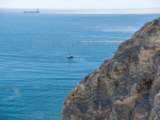 Boat in the middle of the sea sails alone among the waves to the horizon on a late summer day