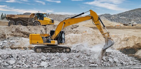 An excavator and a dumper working on a stone embankment