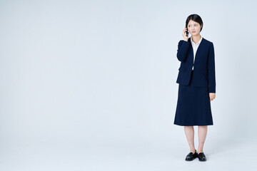 スマートフォンで通話するスーツ姿の若い女性