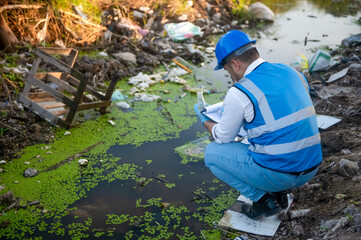 Water resource experts check the water quality in a community canal contaminated with garbage in the canal.