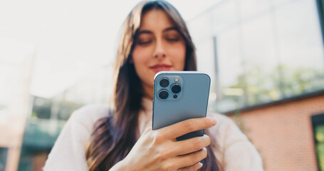 Camera focus on back of smartphone before shifting to Caucasian girls face. Woman holding phone...