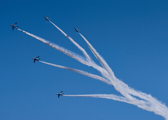 Aerobatics in the blue sky with white contrails.