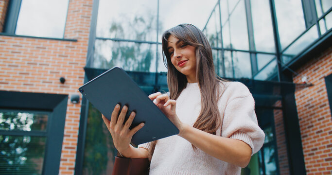 Caucasian woman holding tablet device vertically with one hand. Typing on touch screen. Chatting with someone in social media. Writing text or message. Remotely communicating with boyfriend.