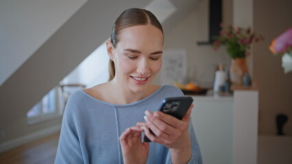 Homely businesswoman watching smartphone social media in sunlit room closeup