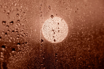 Mocha brown circle of setting sun through drops on glass. Perfect background for your design and inspiration. Selective focus, defocus. Demonstrating color of 2025 year