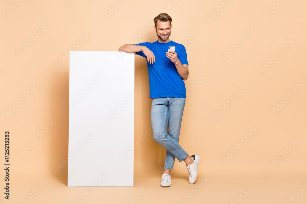 Aufkleber full body portrait of positive blogger man use telephone empty space display isolated on beige color