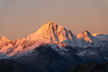 snowy peaks of rocky mountains in the red light of dawn
