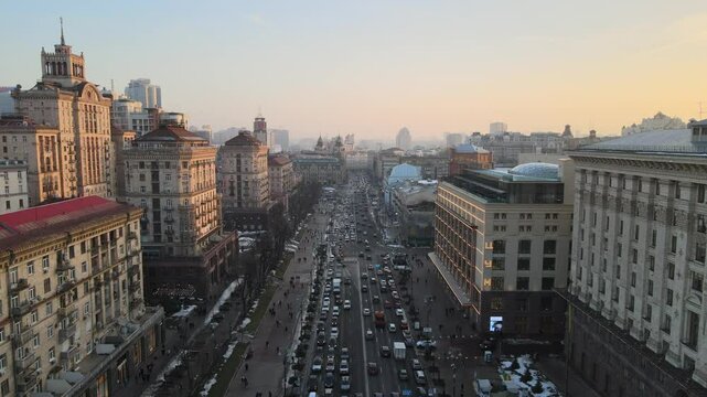 Aerial footage of Khreshchatyk street with a lot of cars, between typical soviet buildings at sunset