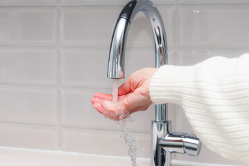 hand checking the temperature of water from kitchen faucet
