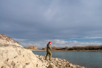 A man on the riverbank is fishing with a spinning rod, a fisherman with a fishing rod on the shore. The angler caught a fish.