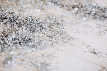 Shiny silver gift wrap fillers scattered on a wooden surface for Christmas 2025