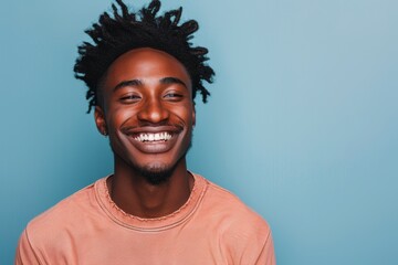 Obraz premium Portrait of a smiling afro-american man in his 20s donning a trendy cropped top in front of pastel blue background