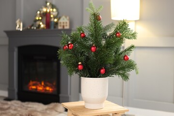 Beautiful Christmas composition of decorated fir tree branches on stool indoors