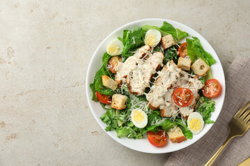 Tasty Caesar salad with chicken and tomatoes in bowl served on gray textured table, flat lay. Space for text
