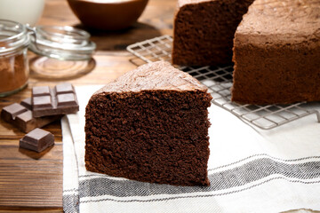 Piece of tasty chocolate sponge cake on wooden table, closeup