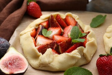 Uncooked galette with strawberries, figs and mint on table, closeup