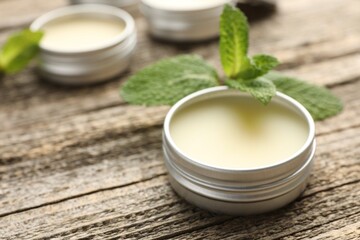 Natural lip balms and mint leaves on wooden background, selective focus. Space for text