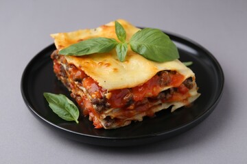 Delicious cooked lasagna with basil on grey table, closeup