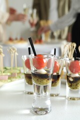 Many different tasty canapes on white table. People enjoying buffet meals indoors, closeup