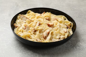 Tasty Alfredo pasta with chicken on light grey table