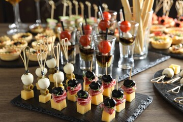 Many different tasty canapes on wooden table, closeup