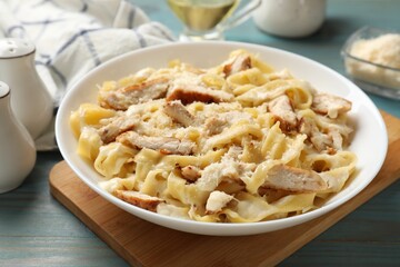 Tasty Alfredo pasta with chicken on light blue wooden table