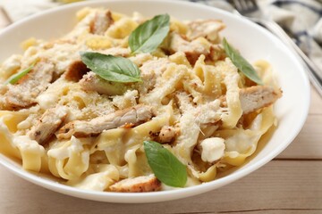 Tasty Alfredo pasta with chicken on light wooden table, closeup