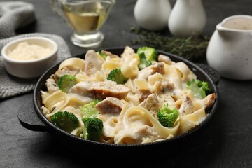 Delicious pasta Alfredo with chicken served on black table, closeup