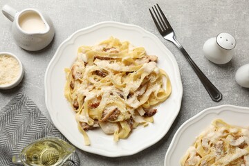 Tasty Alfredo pasta with chicken served on gray textured table, flat lay