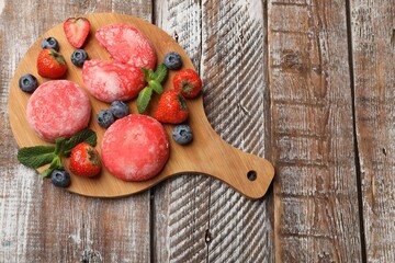 Delicious mochi, strawberries, blueberries and mint on wooden table, top view. Space for text