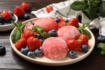 Delicious mochi, strawberries, blueberries and mint on wooden table, closeup