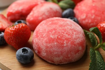 Delicious mochi, strawberries, blueberries and mint on wooden table, closeup