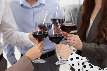 Happy coworkers clinking glasses of wine during office Christmas party, closeup