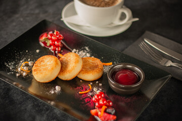 Golden syrniki (cheese pancakes) served with red currants, powdered sugar, fruit garnish