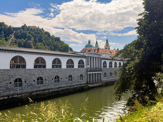 Ljubljana, Slovenia - June 28, 2024: Covered market along the Ljubljanica river under blue...