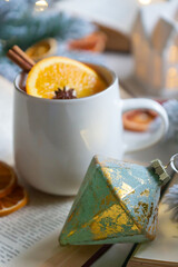 New Year 2025, tea with orange, coffee with marshmallows, books and fir branches, New Year's toys and a ball on the table.