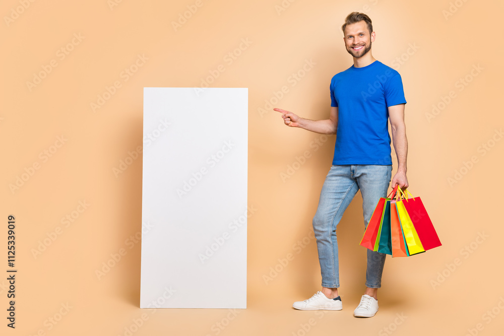 Aufkleber full length portrait of handsome man direct finger empty space display hold packages isolated on bei