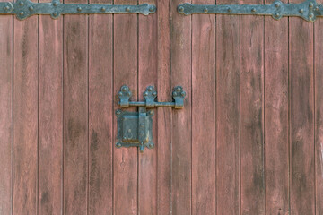 Close-up of a wooden door with intricate iron hinges and a vintage metal latch.