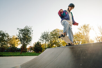 Skateboarder performing trick on ramp at skatepark during sunset