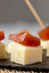 A delicious snack of creamy cheese topped with a slice of quince paste, elegantly presented on a...