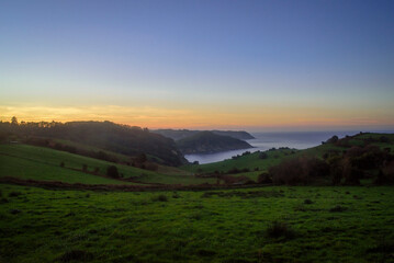 Fototapeta premium Atardecer en bahía tras prados verde en litoral de Asturias