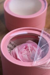 A flower-shaped candle in a mini box with a window in the lid. Gift packaging. Close-up.