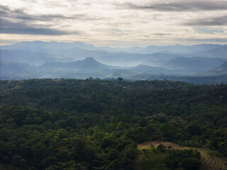 Fototapeta premium Serene view of lush green mountains under cloudy sky at dusk in rural landscape