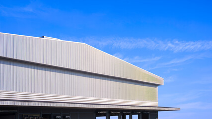 Large Factory Building, Architecture Industrial Warehouse with Corrugated Metal Awning and Gable Roof against Blue Sky Background, Low angle and Perspective Side View