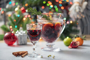 Mulled wine or Holiday Sangria with fresh fruits, cranberries,  pomegranate and spices in a glass on the Christmas decoration. Winter alcoholic drink